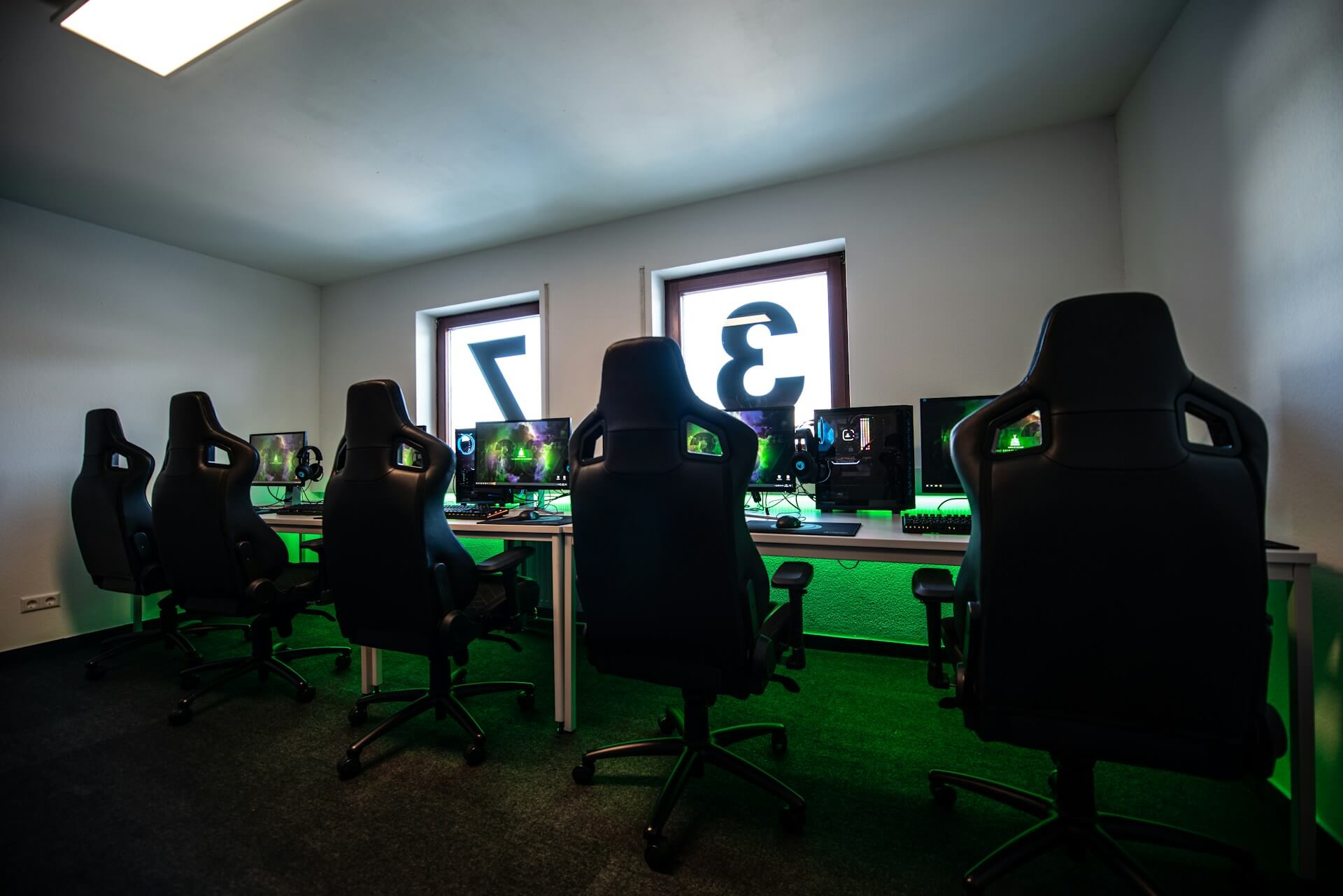 Four gaming chairs and computers lined up in a room.