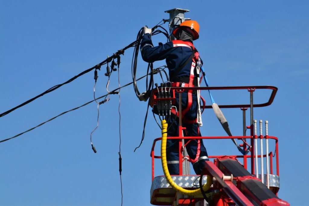 Man wears orange helmet and works on a power line