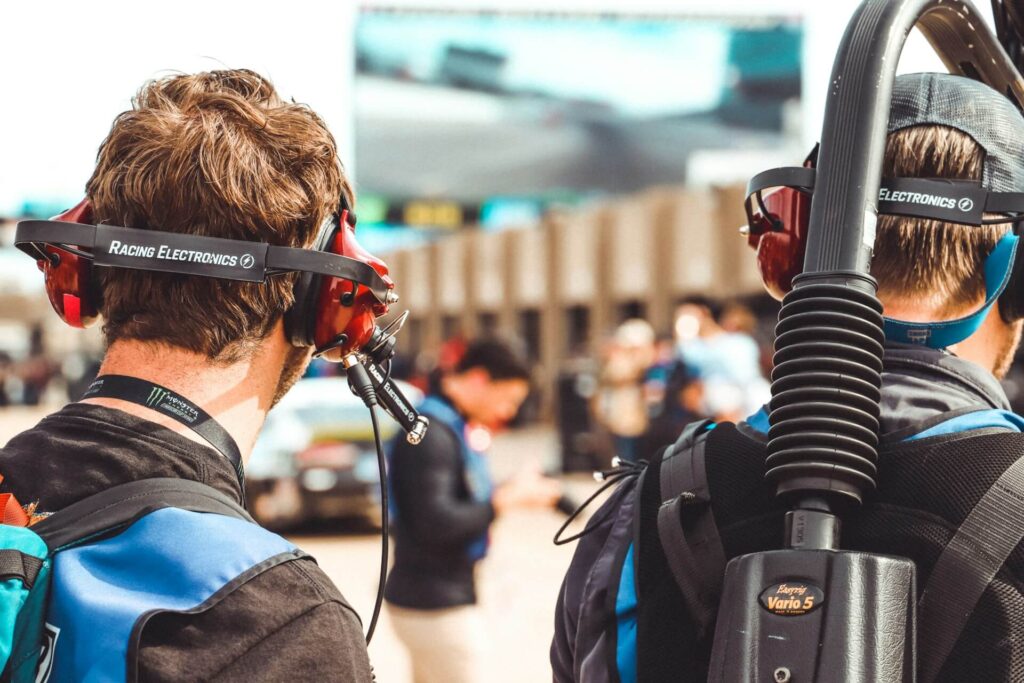 Race team employees with blue and black jackets and headphones