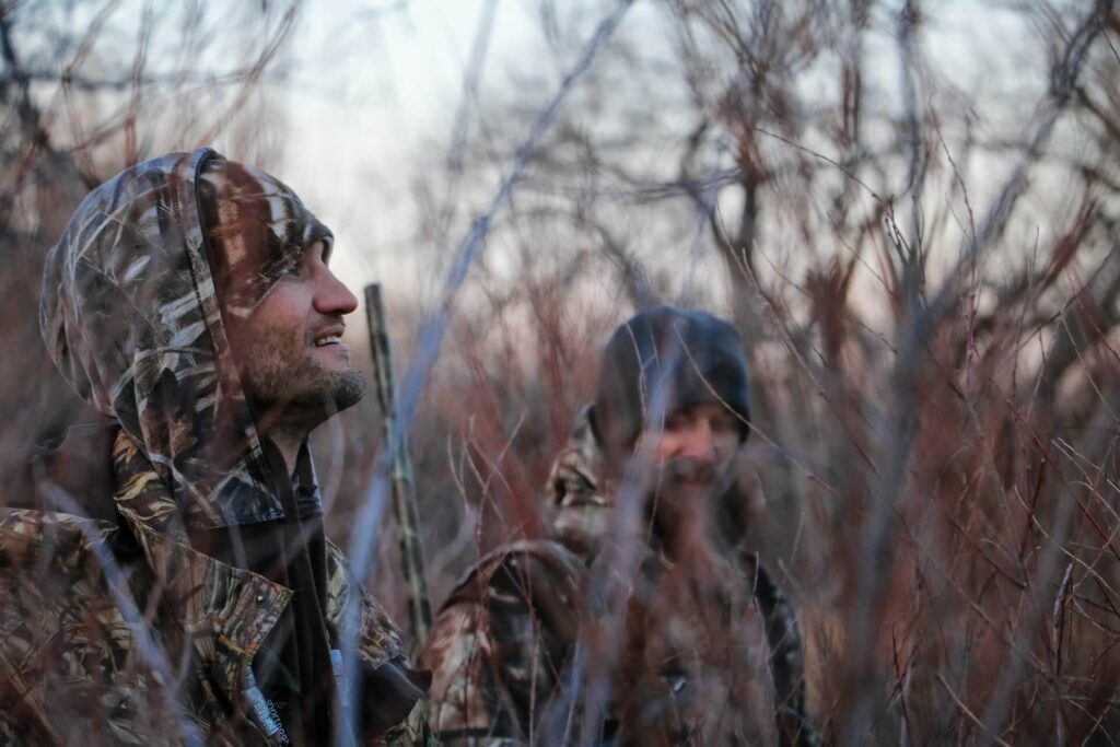 Two men with camouflage hunting in a forest