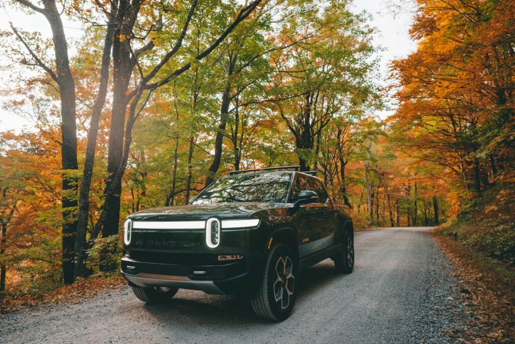 Rivian R1T truck parked on a road surrounded by trees