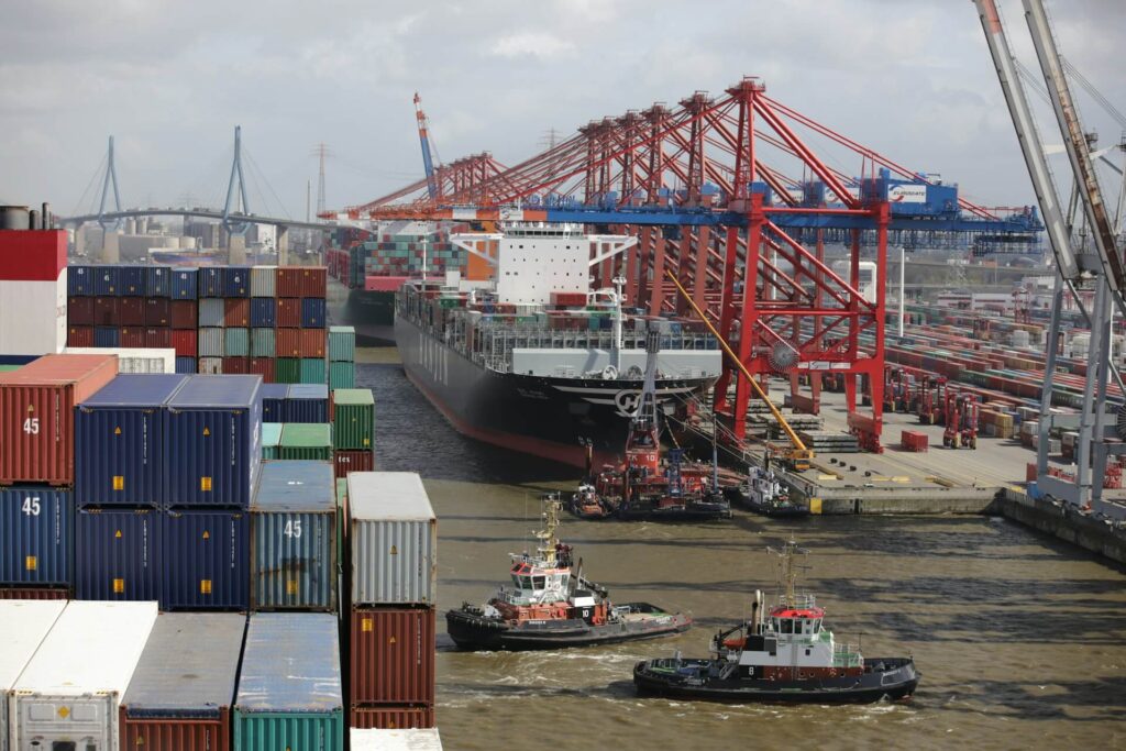 Tug boats in the water next to large cargo ships