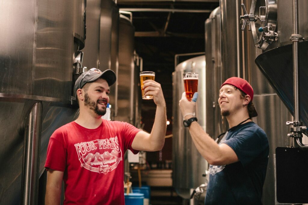 two men holding up fall beers at a brewery