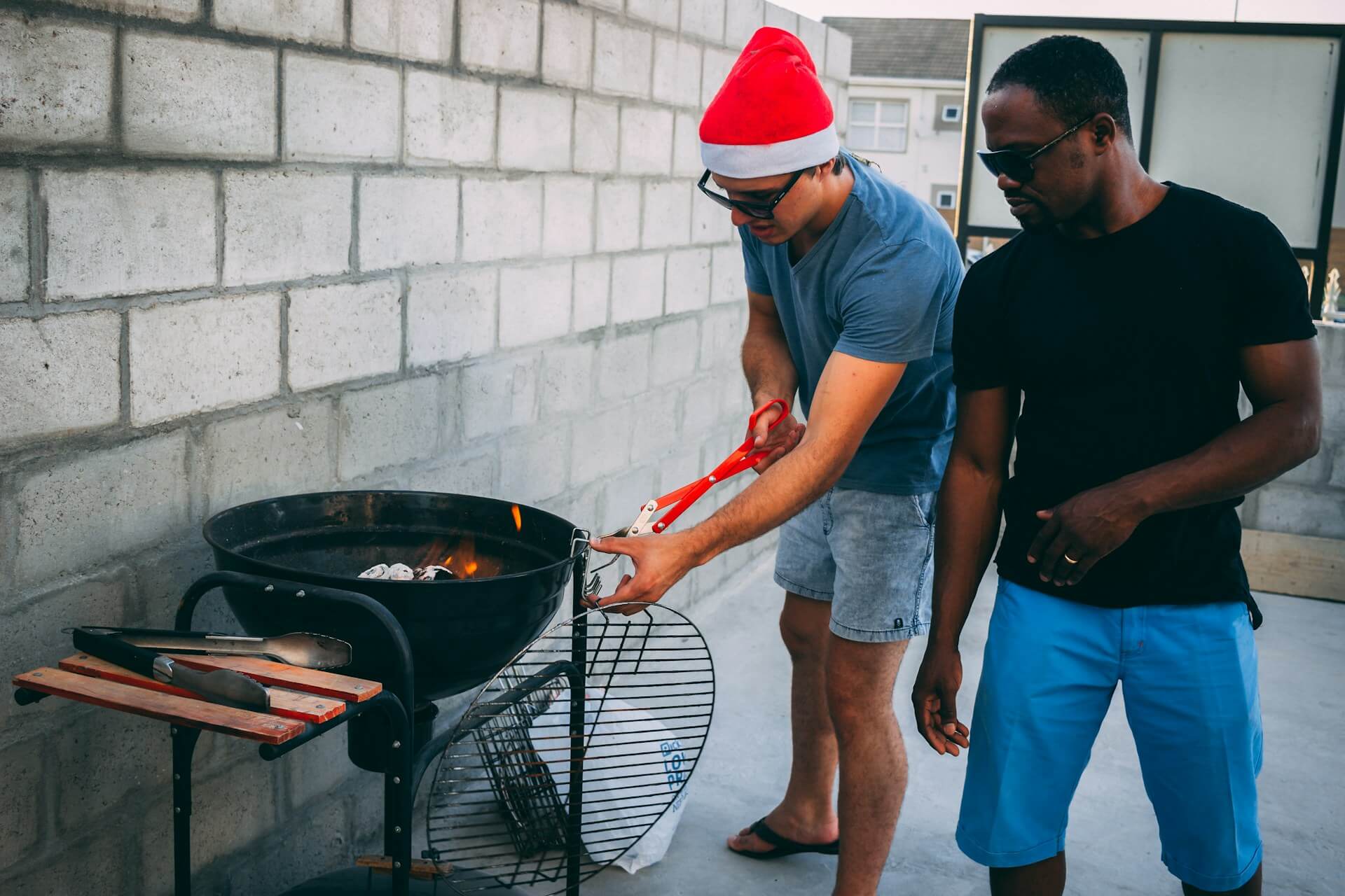 Two men standing next to a charcoal grill