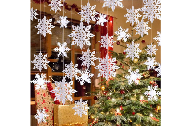 strings of hanging paper snowflakes in front of a decorated living room